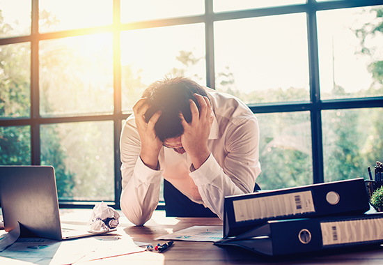 Ein Mann sitzt am Schreibtisch – er benötigt eine Reha bei Burnout